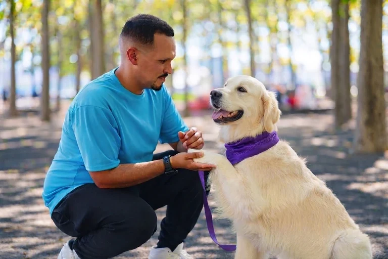 Will Ferman and a golden retriever share a playful moment beneath the trees